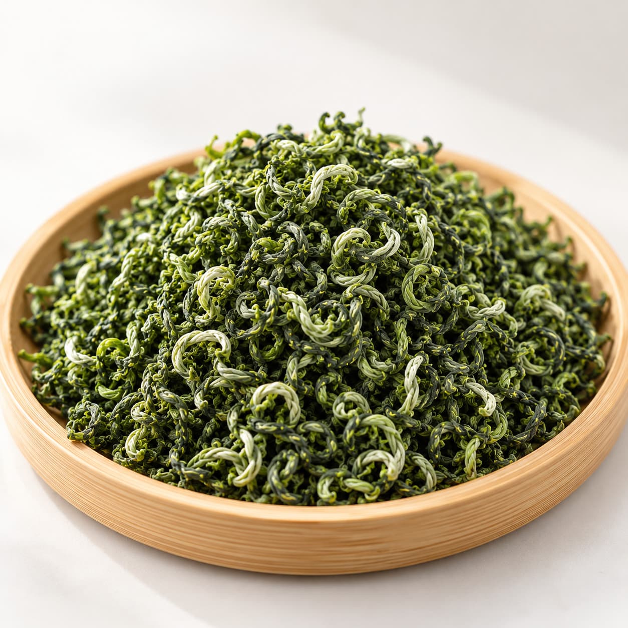 Bi Luo Chun green tea spread on a round bamboo tray.
